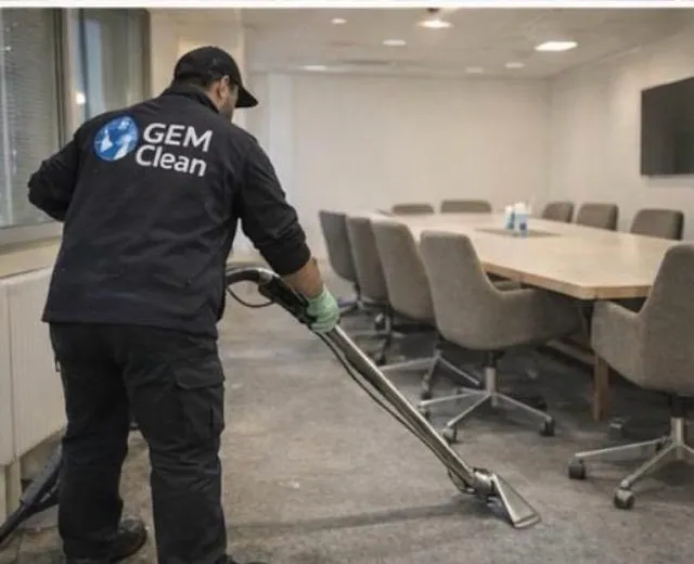 Professionelle Reinigungskräfte in blauer Uniform waschen den Boden und wischen den Staub von der Lampe im Wohnzimmer der Wohnung.